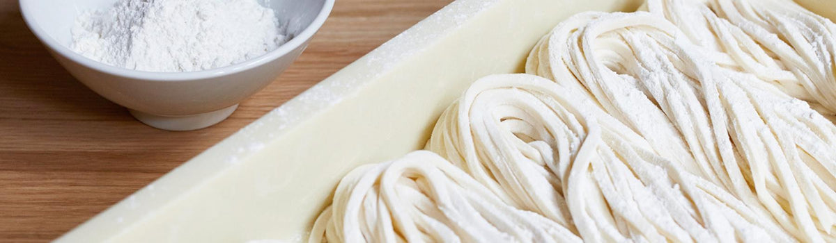 Uncooked udon noodles in a tray