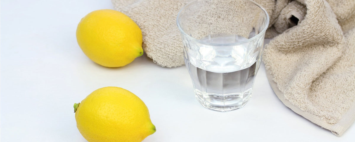 A glass of water and two lemons next to a towel